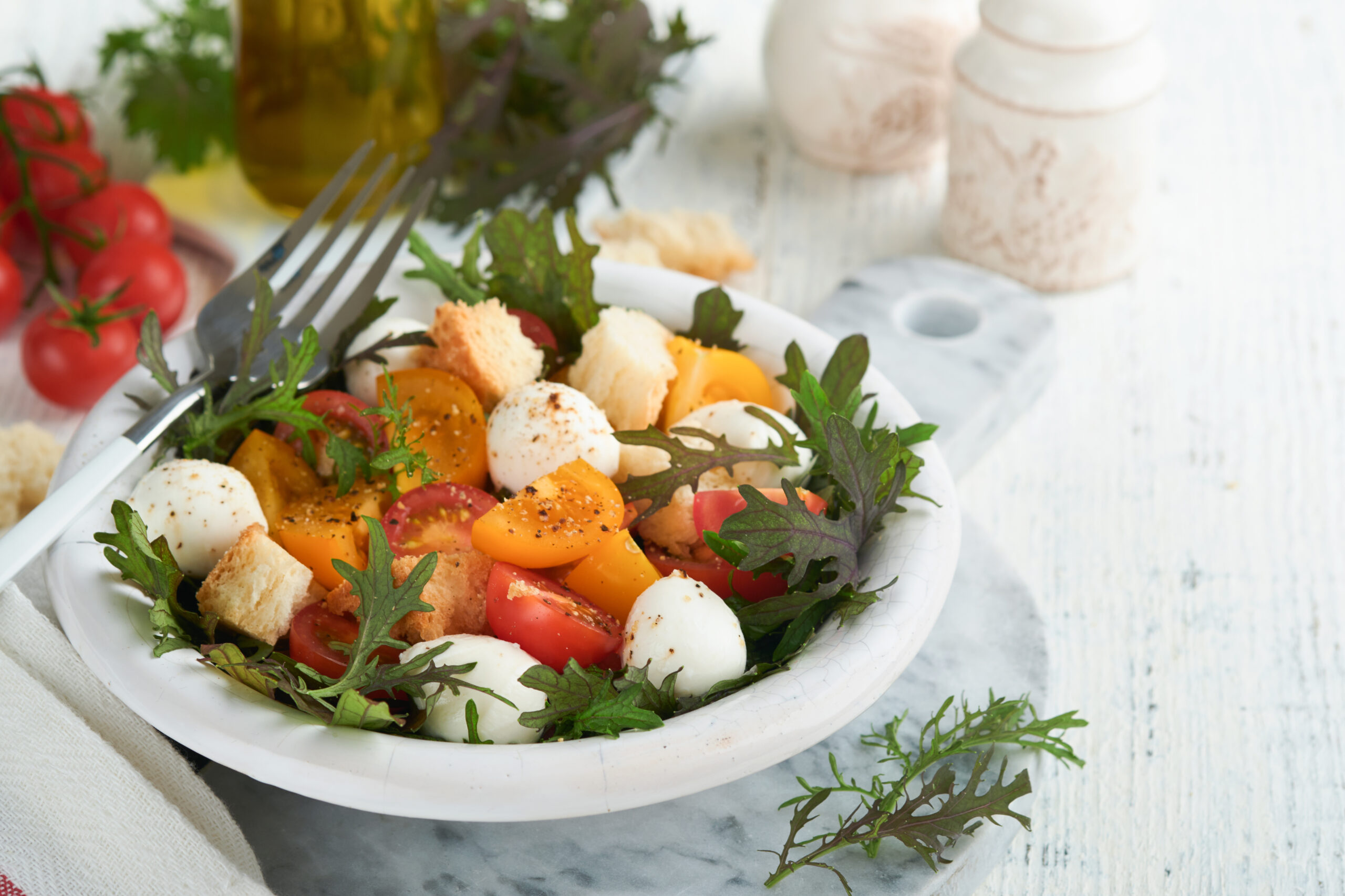 Tuscan Panzanella. Cherry Tomatoes salad with arugula, basil, mozzarella and bread crackers on white bowl. Traditional italian salad. Mediterranean healthy food and cuisine.