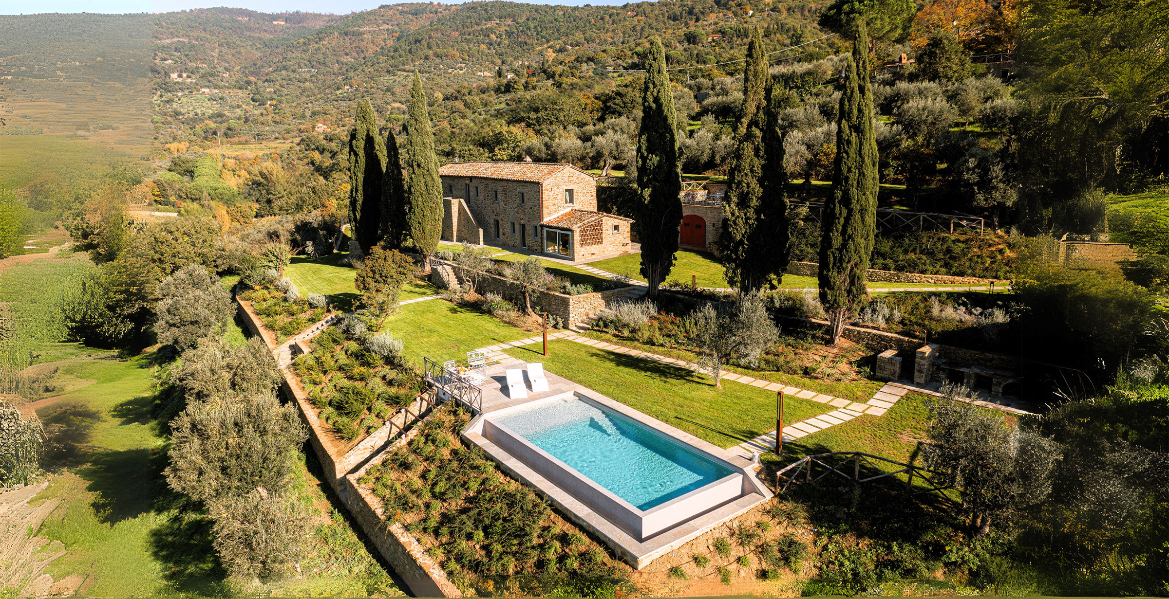 Panoramic overview of the property at Cortona Escape, showing the stone house, private pool, and terraced gardens