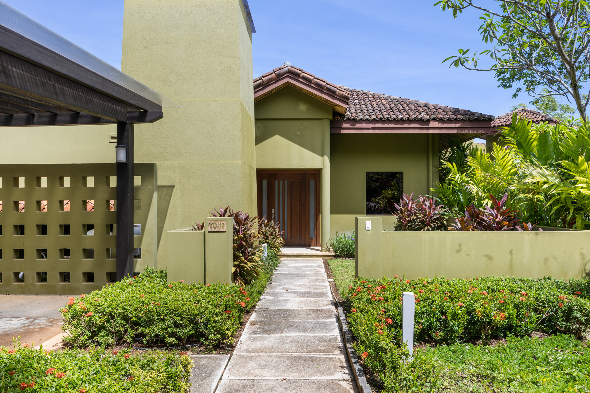 The modern and lush entrance at Villa Conchal, which features an olive green exterior and gorgeous tiled roof