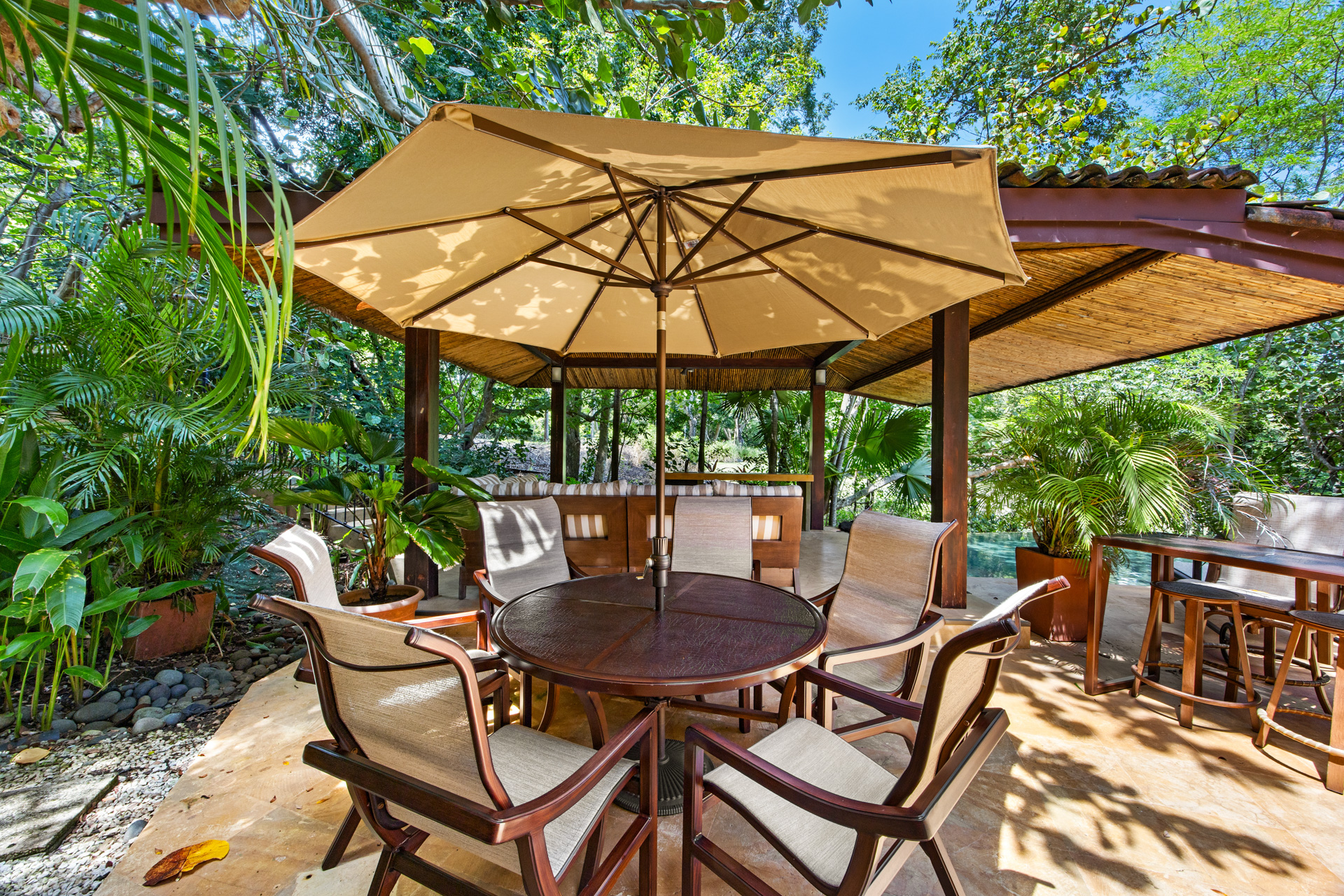 The outdoor dining and gathering areas at Villa Conchal, showing a comfortable round table (seats 6) with an umbrella