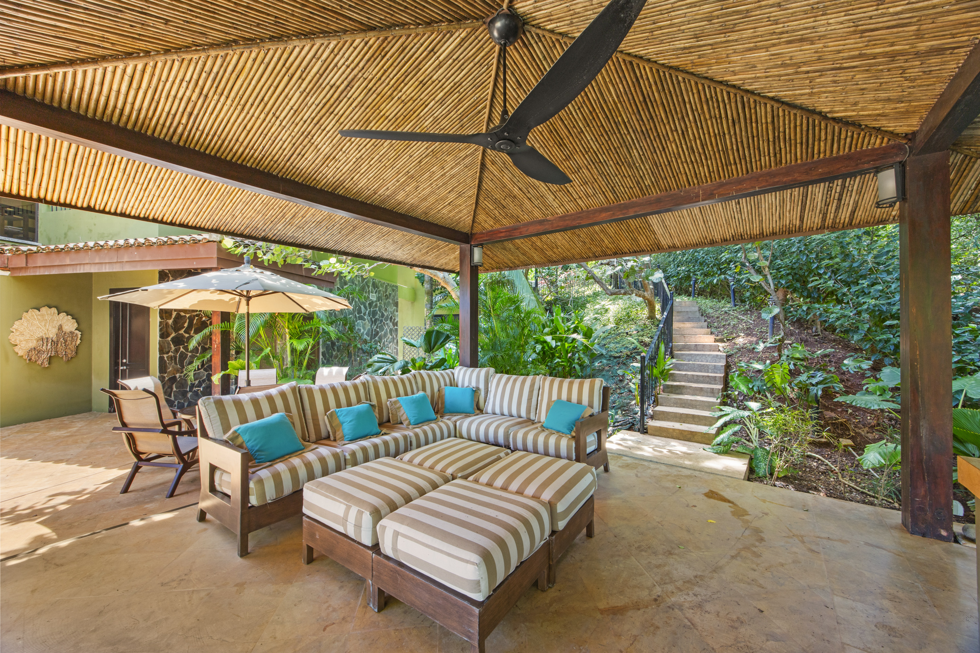 The covered entertaining patio at Villa Conchal, showing the comfy outdoor couch and a dining area beyond